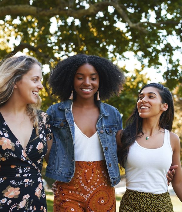Group of smiling happy multiracial female friends walking together happily in the park on a sunny day